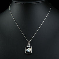 Side angle view of KHAISTA light blue crystal heart pendant necklace