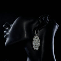 Side angle view of KHAISTA light grey crystal oval drop earrings