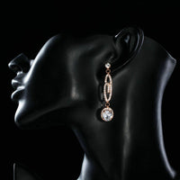 Side angle view of KHAISTA lightweight dangling G-shape drop earrings