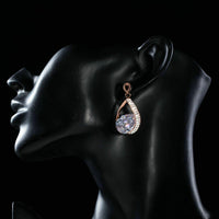 Side angle view of KHAISTA gold plated CZ drop earrings