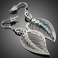 Side angle view of KHAISTA multicolour crystal leaf drop earrings