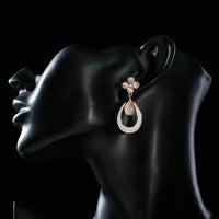 Side angle view of KHAISTA opal flower design drop earrings