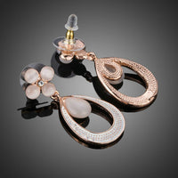 Close up of KHAISTA opal flower design drop earrings