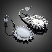 Close up of KHAISTA opal CZ drop earrings
