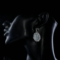 Side angle view of KHAISTA opal CZ drop earrings