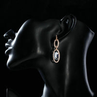 Side angle view of KHAISTA oval chain link crystal drop earrings