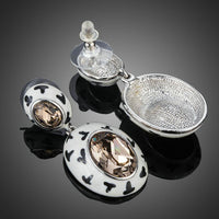 Close up of KHAISTA oval crystal pave drop earrings