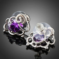 Side angle view of KHAISTA oval purple CZ stud earrings