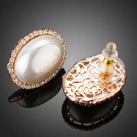 Side angle view of KHAISTA oval shell pearl stud earrings