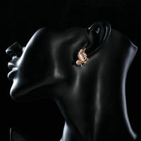 Side angle view of KHAISTA peach crystal clip earrings