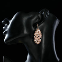 Side angle view of KHAISTA peach crystal oval drop earrings
