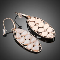 Close up of KHAISTA peach crystal oval drop earrings