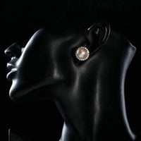 Side angle view of KHAISTA peach pearl dome stud earrings
