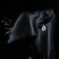 Side angle view of KHAISTA pear shaped CZ drop earrings
