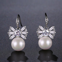 Side angle view of KHAISTA pearl bow knot drop earrings