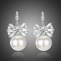 KHAISTA pearl bow knot drop earrings on white background
