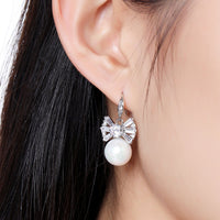 Close up of KHAISTA pearl bow knot drop earrings