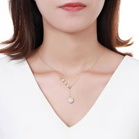 Side angle view of KHAISTA pearl sunflower pendant necklace