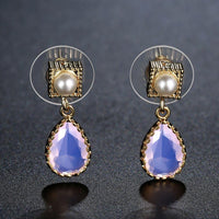 Close up of KHAISTA pink opal crystal drop earrings