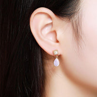 Side angle view of KHAISTA pink opal crystal drop earrings