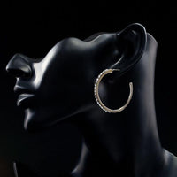 Side angle view of KHAISTA platinum plated bangle design drop earrings