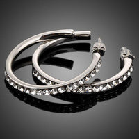 Close up of KHAISTA platinum plated bangle design drop earrings
