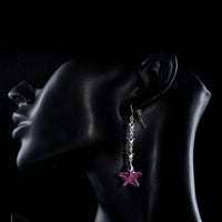 Side angle view of KHAISTA purple crystal star drop earrings