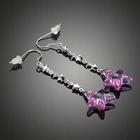 Close up of KHAISTA purple crystal star drop earrings