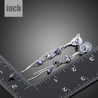 Side angle view of KHAISTA purple CZ drop earrings