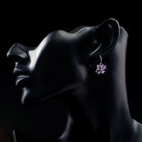 Side angle view of KHAISTA purple daisy crystal stud earrings
