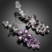 Side angle view of KHAISTA purple flower cluster drop earrings