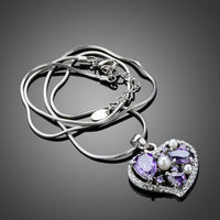 Side angle view of KHAISTA purple crystal heart pendant necklace