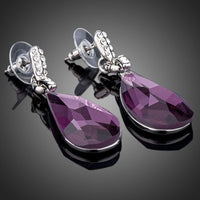 Close up of KHAISTA purple raindrop crystal drop earrings