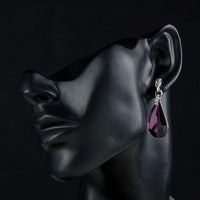 Side angle view of KHAISTA purple raindrop crystal drop earrings
