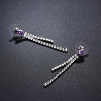 Side angle view of KHAISTA purple crystal tassel dangle earrings