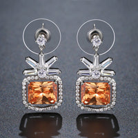 Close up of KHAISTA rectangle cut champagne drop earrings