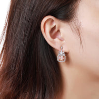 Side angle view of KHAISTA rectangle cut champagne drop earrings