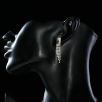 Side angle view of KHAISTA rectangle dangle drop earrings