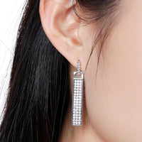 Close up of KHAISTA rectangle paved CZ dangle earrings