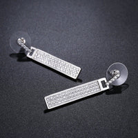 Side angle view of KHAISTA rectangle paved CZ dangle earrings