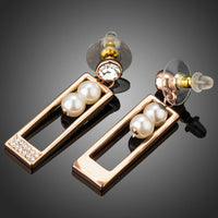 Side angle view of KHAISTA rose gold rectangle pearl drop earrings