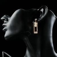 Close up of KHAISTA rose gold rectangle pearl drop earrings