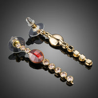 Close up of KHAISTA red crystal oval dangle drop earrings