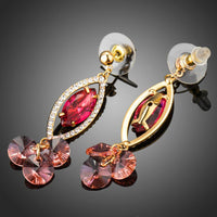 Side angle view of KHAISTA red CZ dangle earrings