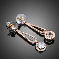 Side angle view of KHAISTA rose gold CZ drop earrings