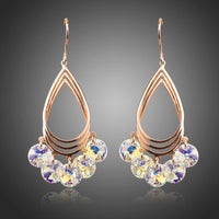 KHAISTA rose gold crystal dangle earrings on white background