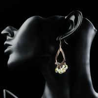 Close up of KHAISTA rose gold crystal dangle earrings