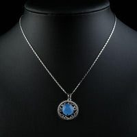 Side angle view of KHAISTA round blue opal pendant necklace
