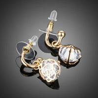Close up of KHAISTA round cage CZ dangle drop earrings