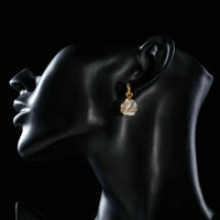 Side angle view of KHAISTA round cage CZ dangle drop earrings